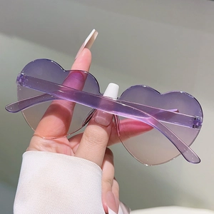 Close-up of heart-shaped sunglasses with purple gradient lenses and translucent frame