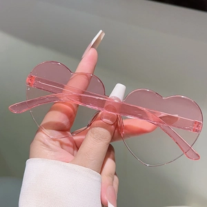 Close-up of pink rimless heart sunglasses with transparent resin lenses and temples