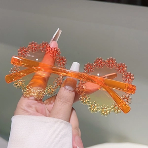 Close-up of orange translucent daisy flower sunglasses for kids in hand