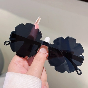 Macro detail of black flower-shaped sunglasses with wavy rimless edges for kids