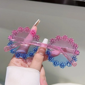 Detail of kids flower round sunglasses with pink frames and colorful daisy floral decor