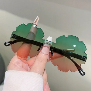 Detail of flower-shaped children's sunglasses with green-orange gradient rimless lenses