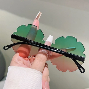 Detail of rimless flower-shaped sunglasses with pink gradient lenses and black temples