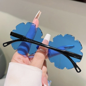 Detailed close-up of blue petal-shaped rimless sunglasses for kids with black temples
