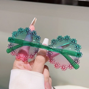 Close-up of kids floral round sunglasses with green to pink gradient frame and petal details
