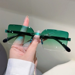 Detail of frameless rectangle sunglasses with green gradient lenses held by hand