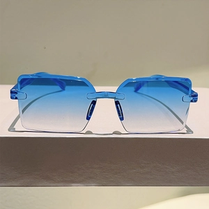 Detail view of frameless square sunglasses with blue gradient lenses on a white pedestal