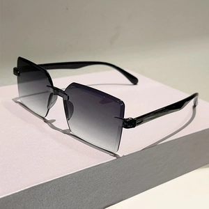 Detail view of rimless square sunglasses with gradient grey lenses on a minimalist stand