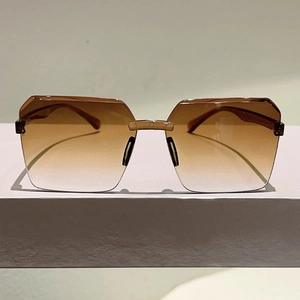 Detail of rimless jelly sun glasses with brown gradient lenses and metal bridge connector