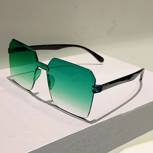 Detail view of oversized rimless sunglasses featuring green gradient lenses and black temples