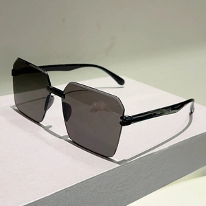 Detailed close-up of geometric frameless sunglasses with dark irregular cut-edge lenses