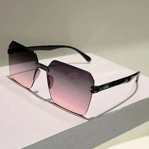 Detail view of oversized rimless gradient purple and pink sunglasses on display stand
