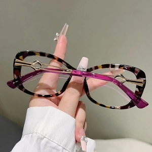 Detailed view of cat-eye glasses with tortoiseshell frames and gold hollow-out hinges