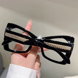 Detailed view of black eyeglass frames with gold woven textured metal accents on temples