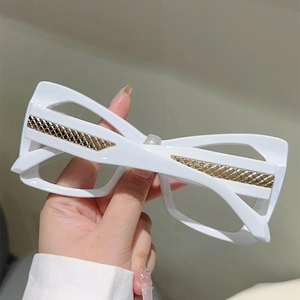 Detail shot of white cat-eye glasses featuring gold woven texture on the temple