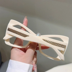 Close-up of cream cat-eye glasses frame with elegant gold braided metal detail