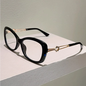 Detail of black cat-eye glasses frame featuring gold metal temples with hollow knot design
