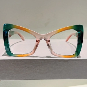Macro detail of cat-eye eyewear showing the vibrant orange and green gradient color frame