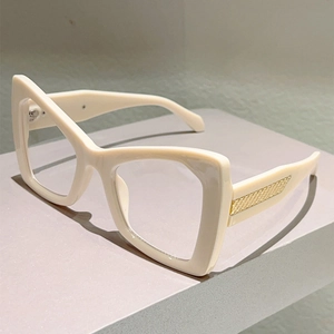 Close-up of cream cat-eye glasses frame featuring gold textured metal temple accents