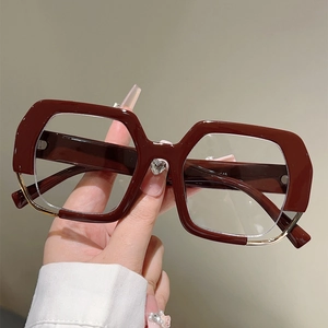 Close-up of wine red oversized frame glasses featuring a heart-shaped crystal on bridge