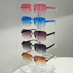 Cinq paires de lunettes de soleil dégradées sans monture présentées sur un support en acrylique