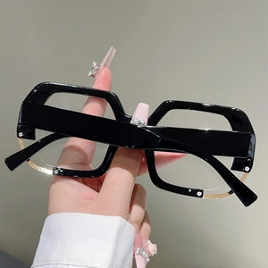 Close-up of stylish irregular black oversized frames with gold rim and metal rivet details
