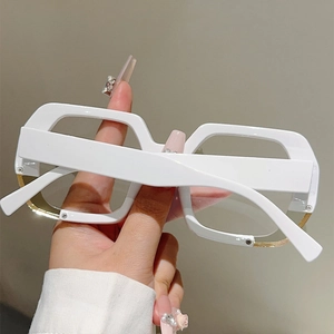 Detail of white oversized frame glasses with golden metal trim and wide temple design