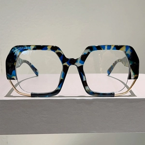 Detail of oversized irregular eyewear frame with blue tortoiseshell pattern and gold metal