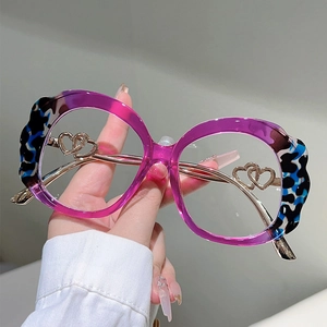 Detail of round glasses with purple frame and hollow heart metal decoration on temple