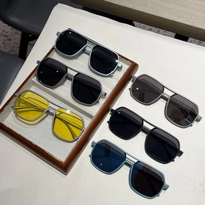 Close-up of double-bridge pilot sunglasses in various frame and lens colors on a tray