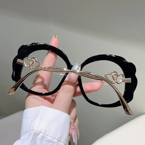 Detail of gold metal temples with hollow double heart design on oversized black glasses