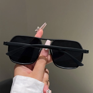 Detail of matte black double bridge sunglasses with large square frames and geometric lenses