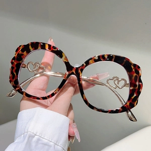 Detailed view of leopard print round glasses frame with gold hollow heart metal ornament