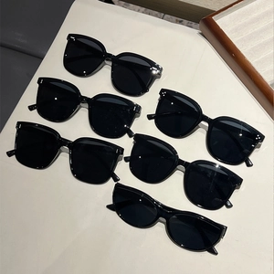 Close-up of various black cat-eye and square sunglasses arranged on a white surface