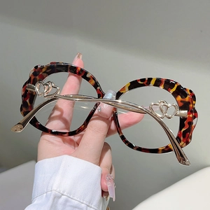 Close-up of leopard print round glasses frame with wavy edges and gold heart metal temples