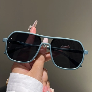 Close-up of matte teal square sunglasses with a double-bridge frame and dark lenses