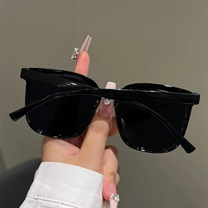 Detail view of glossy black cat-eye sunglasses with dark tinted lenses and smooth frame