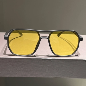 Close-up of minimalist square sunglasses with black frame and yellow lenses for men