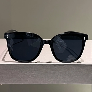 Classic black cat-eye sunglasses with silver rivets on a premium gray display stand