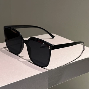 Detail of glossy black cat-eye sunglasses featuring iconic vertical metal studs