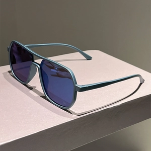 Macro side view of matte blue pilot sunglasses with gradient lenses on a minimalist stand