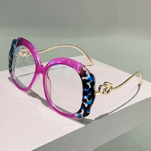 Detail of blue leopard print eyeglass frame with golden heart-shaped metal temple decor