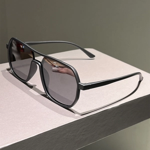 Detail view of matte black double bridge aviator sunglasses on a minimalist stand