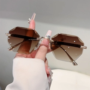 Close-up of rimless hexagonal sunglasses with brown gradient lenses and gold frames