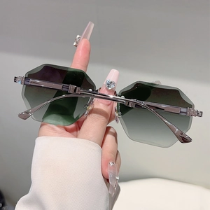 Detail of rimless hexagonal sunglasses with gradient green lenses and silver metal temples