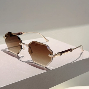 Close-up of rimless hexagonal sunglasses with diamond-cut brown gradient lenses and gold frames