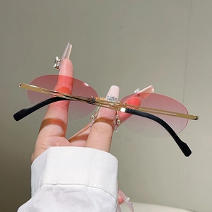 Close-up of pink gradient rimless oval sunglasses with thin gold metal temples
