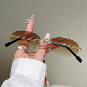 Detail of rimless oval sunglasses with brown gradient lenses and thin gold metal temples
