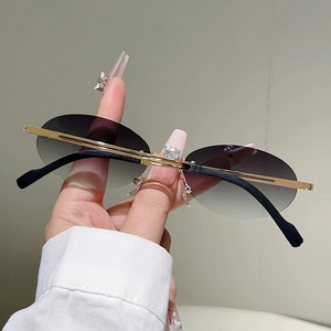 Close-up of rimless oval sunglasses with gradient grey lenses and slim gold metal temples