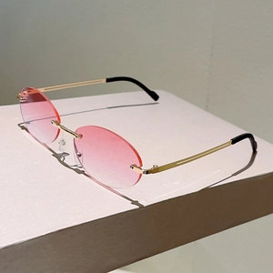 Detailed macro view of rimless oval sunglasses with pink gradient lenses and gold metal temples